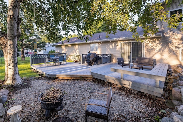 rear view of house with a shingled roof, a fire pit, and a deck