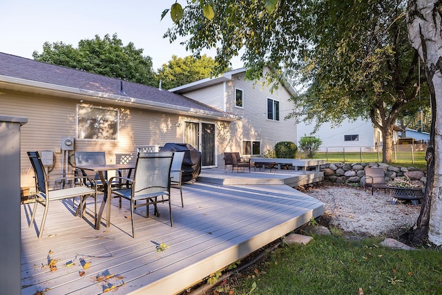 wooden terrace featuring outdoor dining space, fence, and a grill