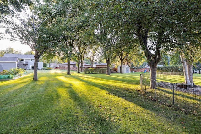 view of yard featuring an outbuilding, fence, and a shed