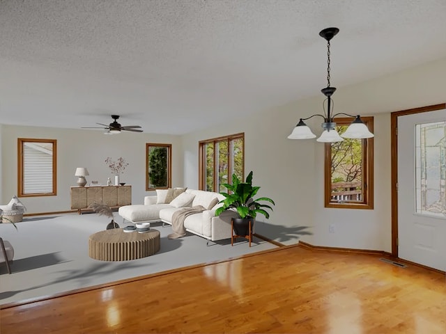 unfurnished living room featuring baseboards, light wood-style flooring, visible vents, and a textured ceiling