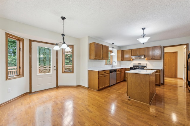 kitchen with stainless steel appliances, light countertops, light wood-style floors, plenty of natural light, and under cabinet range hood