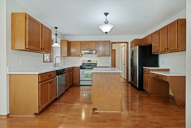 kitchen with stainless steel appliances, light countertops, under cabinet range hood, and light wood finished floors