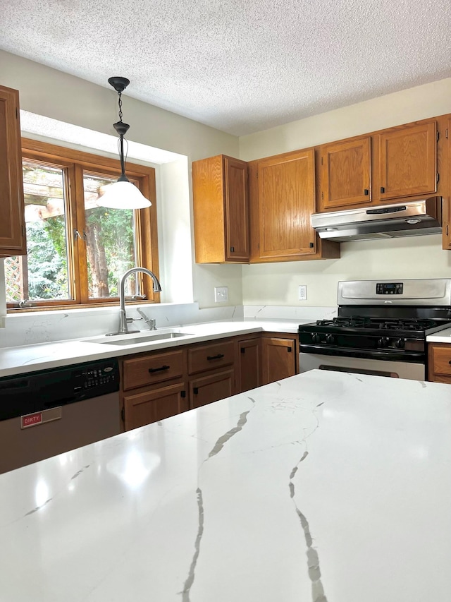 kitchen with under cabinet range hood, a sink, hanging light fixtures, appliances with stainless steel finishes, and brown cabinets