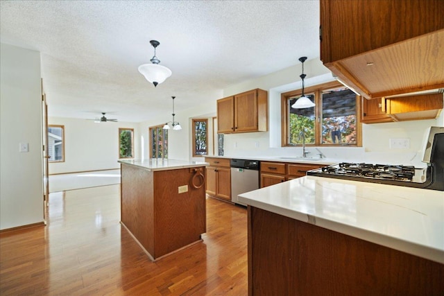 kitchen featuring a sink, a center island, dishwasher, light wood finished floors, and brown cabinetry