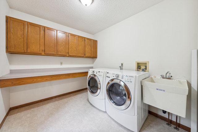 laundry area featuring washing machine and dryer, a sink, baseboards, cabinet space, and light floors