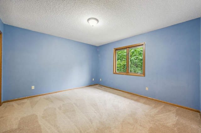 carpeted spare room featuring a textured ceiling and baseboards