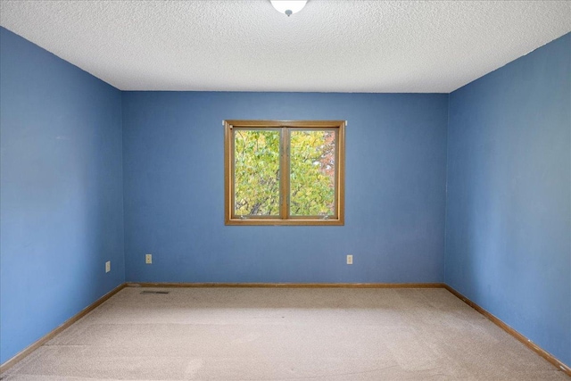 spare room featuring a textured ceiling, carpet flooring, and baseboards