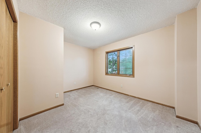 carpeted empty room with a textured ceiling and baseboards