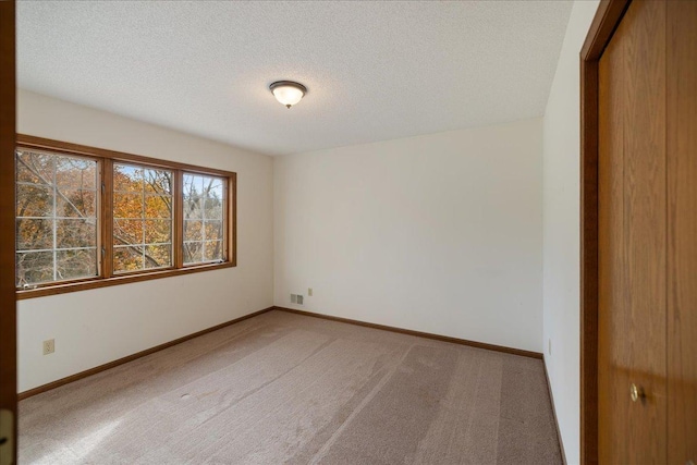 carpeted spare room with visible vents, a textured ceiling, and baseboards