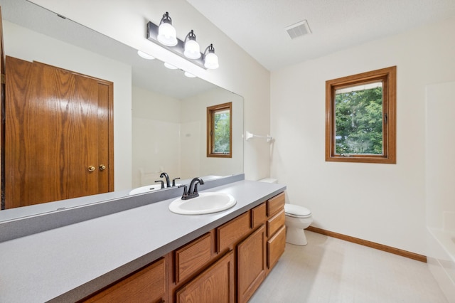 bathroom featuring visible vents, toilet, vanity, baseboards, and walk in shower