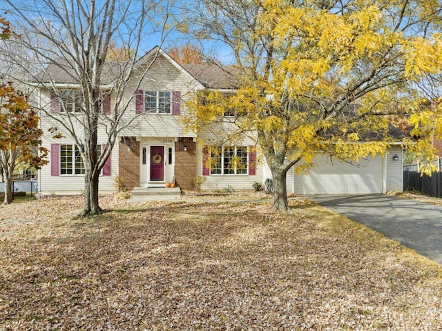 view of front of house with a garage, brick siding, driveway, and fence