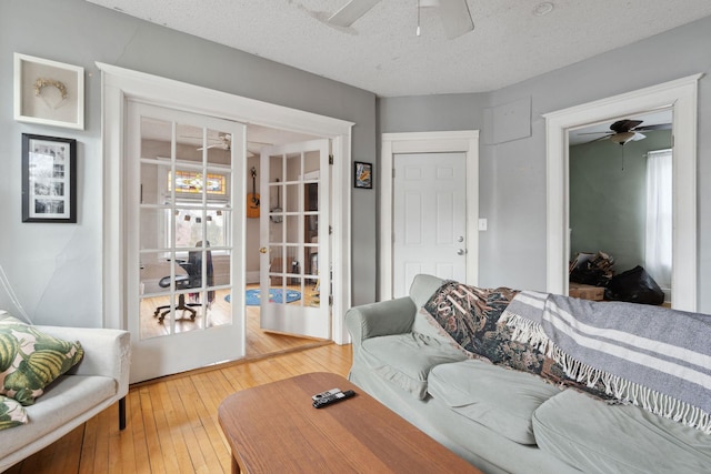 living area with ceiling fan, french doors, a textured ceiling, and hardwood / wood-style flooring