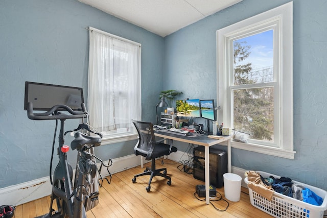 home office with baseboards, hardwood / wood-style floors, and a textured wall