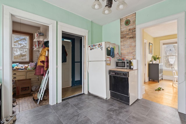 kitchen featuring dishwasher, stainless steel microwave, a chandelier, and freestanding refrigerator