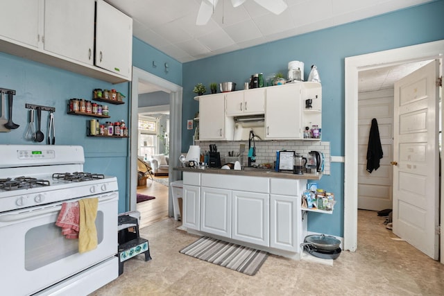 kitchen featuring ceiling fan, white cabinets, decorative backsplash, open shelves, and white gas range