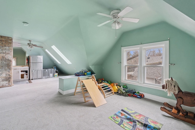 playroom featuring vaulted ceiling with skylight, carpet, and a ceiling fan