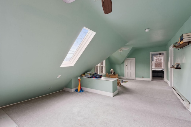 bonus room featuring carpet floors, vaulted ceiling with skylight, baseboard heating, and a ceiling fan