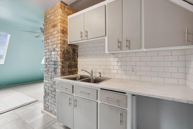 kitchen with tasteful backsplash, ceiling fan, tile patterned floors, gray cabinets, and a sink