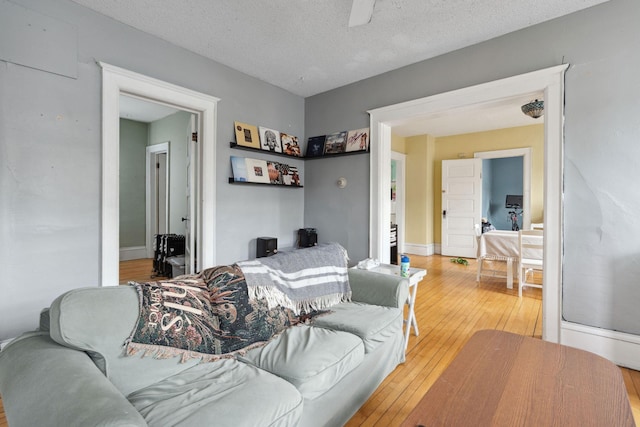 living area featuring light wood-style flooring, baseboards, and a textured ceiling