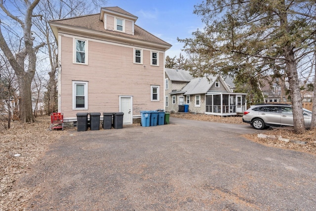 view of home's exterior with a shingled roof and a sunroom