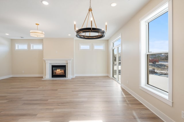 unfurnished living room featuring a fireplace with flush hearth, light wood-type flooring, baseboards, and recessed lighting