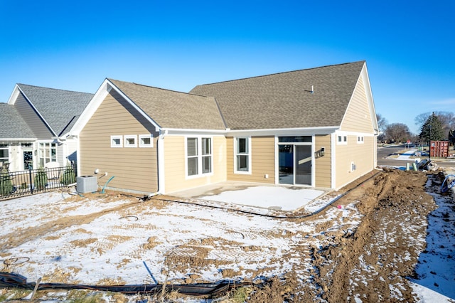 snow covered property featuring a patio, a shingled roof, fence, and central air condition unit