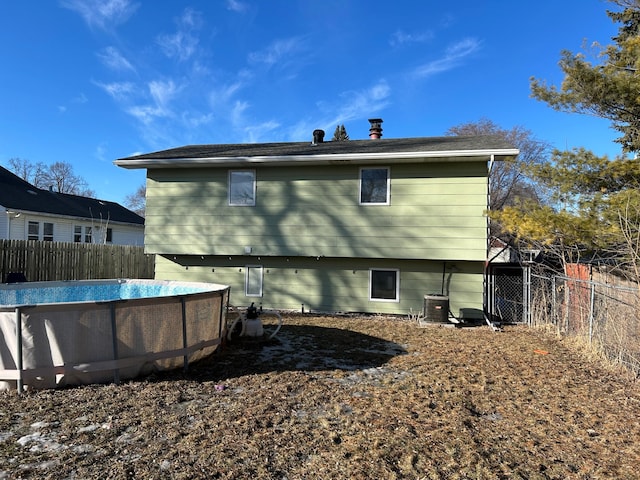 back of property with cooling unit, a fenced in pool, and fence