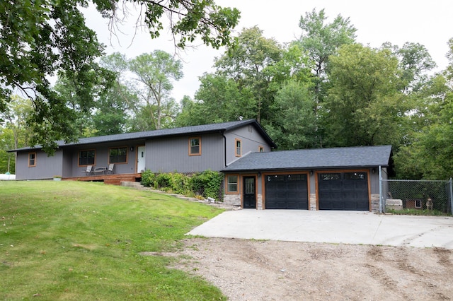 view of front of property with driveway, stone siding, an attached garage, and a front yard