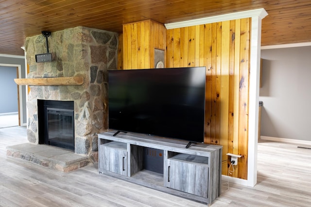 unfurnished living room featuring a stone fireplace, wood finished floors, wood ceiling, baseboards, and ornamental molding