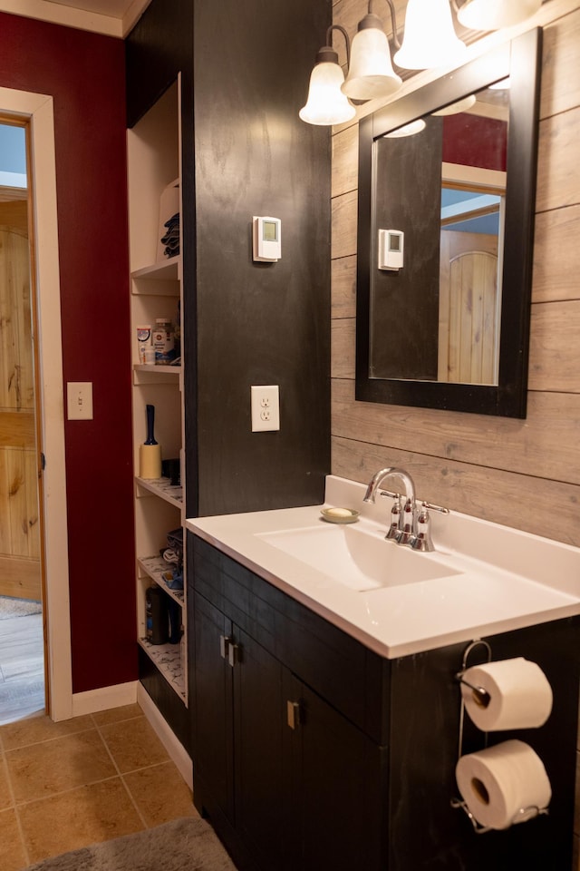 bathroom featuring tile patterned flooring, wooden walls, baseboards, and vanity