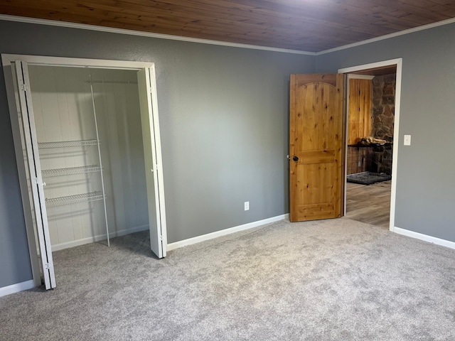 unfurnished bedroom featuring carpet floors, a closet, ornamental molding, wooden ceiling, and baseboards