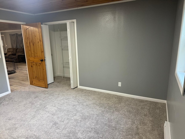 unfurnished bedroom with a baseboard heating unit, carpet, baseboards, and crown molding