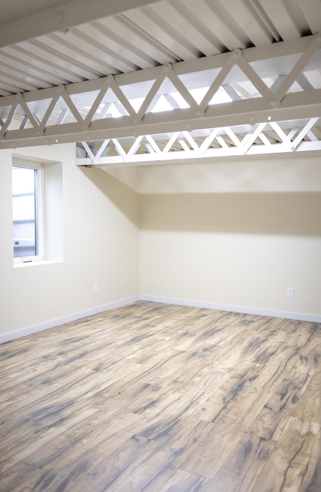 unfurnished room featuring lofted ceiling with beams, wood finished floors, and baseboards