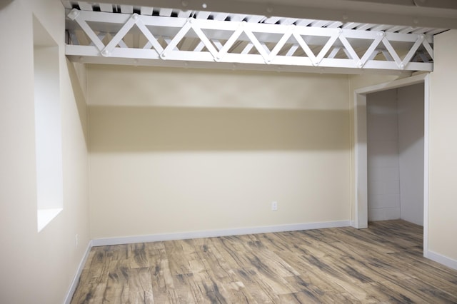 unfurnished bedroom with a dry bar, wood finished floors, and baseboards