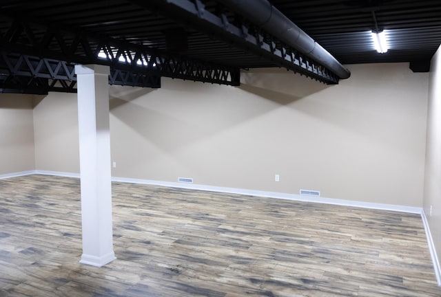 basement with visible vents, baseboards, and wood finished floors