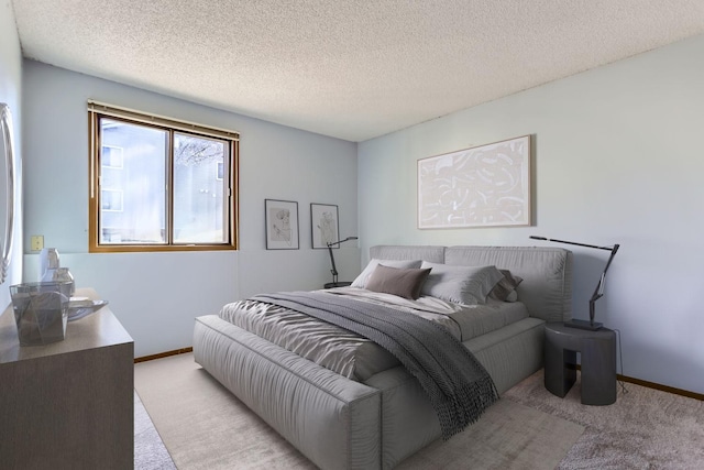 bedroom with baseboards, a textured ceiling, and light colored carpet