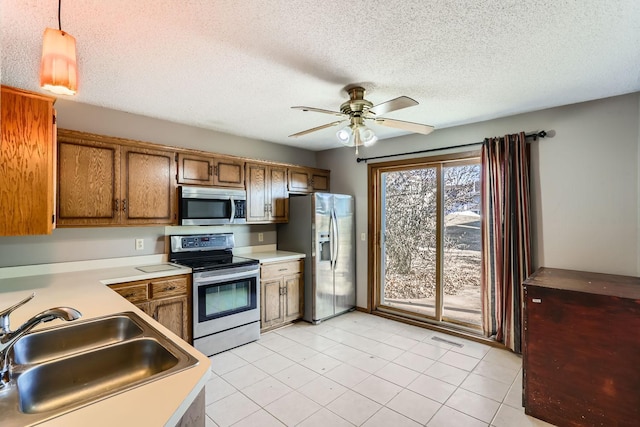 kitchen featuring stainless steel appliances, light countertops, visible vents, brown cabinetry, and a sink