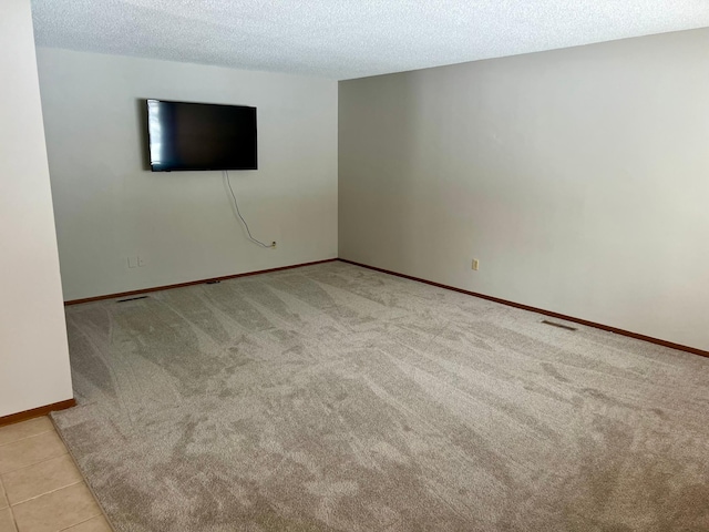 tiled spare room with carpet, baseboards, and a textured ceiling