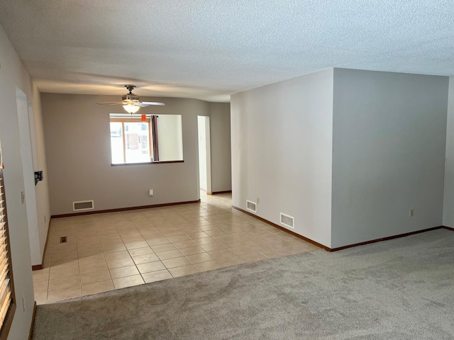 empty room featuring light tile patterned floors, visible vents, and light colored carpet