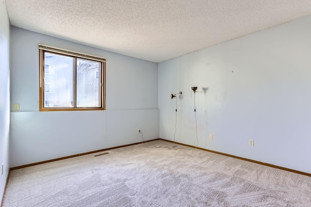 carpeted spare room with baseboards, visible vents, and a textured ceiling