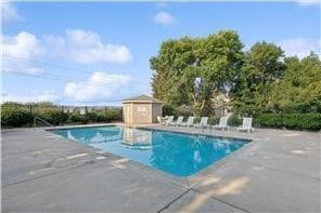 pool featuring a patio area, an outdoor structure, and a storage unit