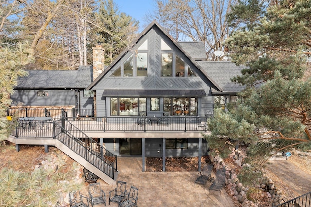 back of house featuring a wooden deck, a chimney, stairway, and roof with shingles