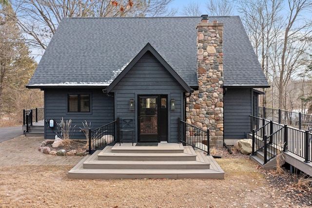 chalet / cabin featuring a shingled roof and a chimney