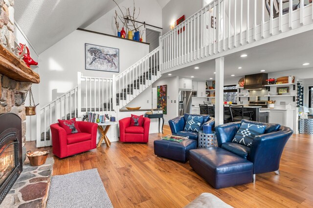 living room featuring a fireplace, stairway, a towering ceiling, and wood finished floors