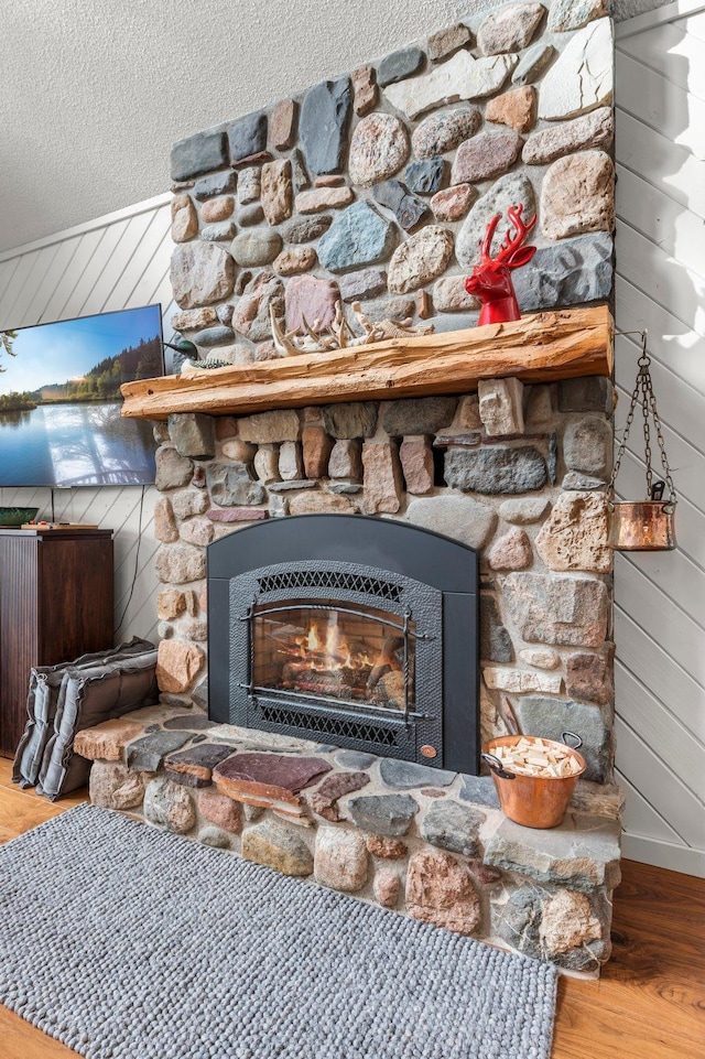 interior details with wooden walls, a fireplace, wood finished floors, and a textured ceiling