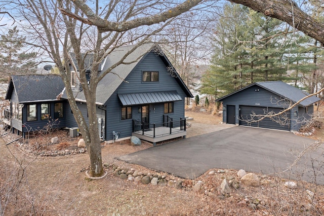 view of front of house with a garage, a shingled roof, an outbuilding, covered porch, and central AC