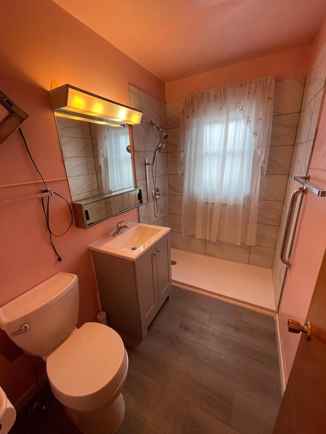 full bath featuring vanity, a shower stall, toilet, and wood finished floors