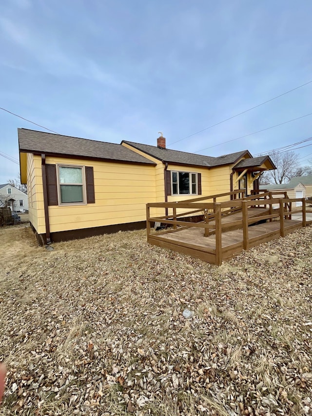 rear view of property featuring a chimney and a deck