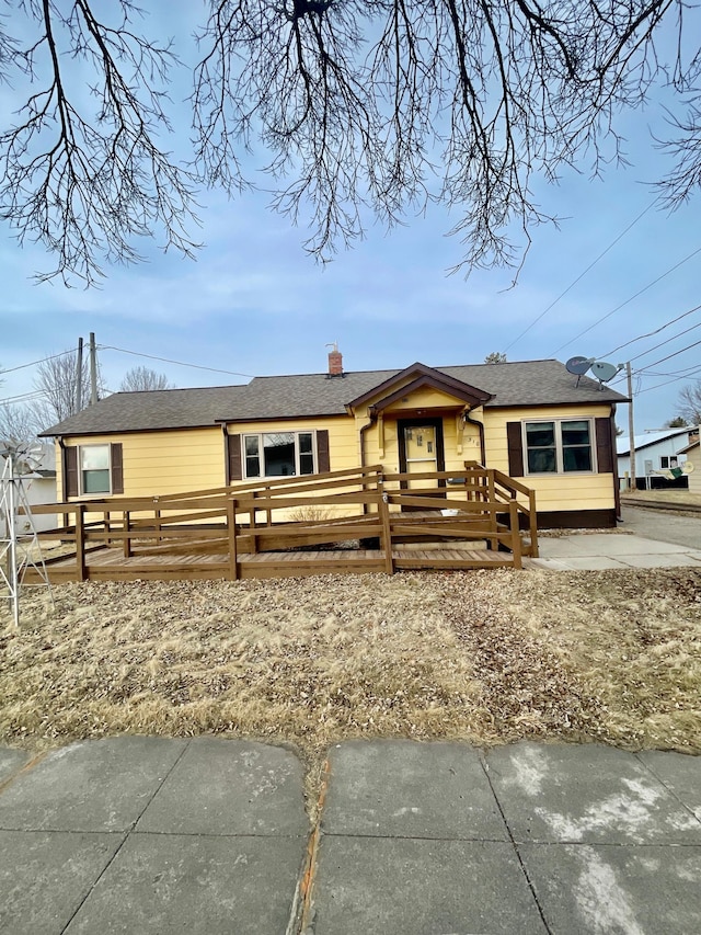 ranch-style house with a fenced front yard, roof with shingles, and a chimney