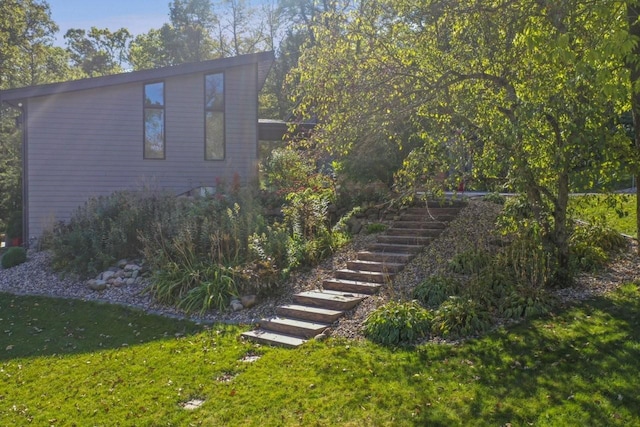 view of home's exterior with stairs and a lawn